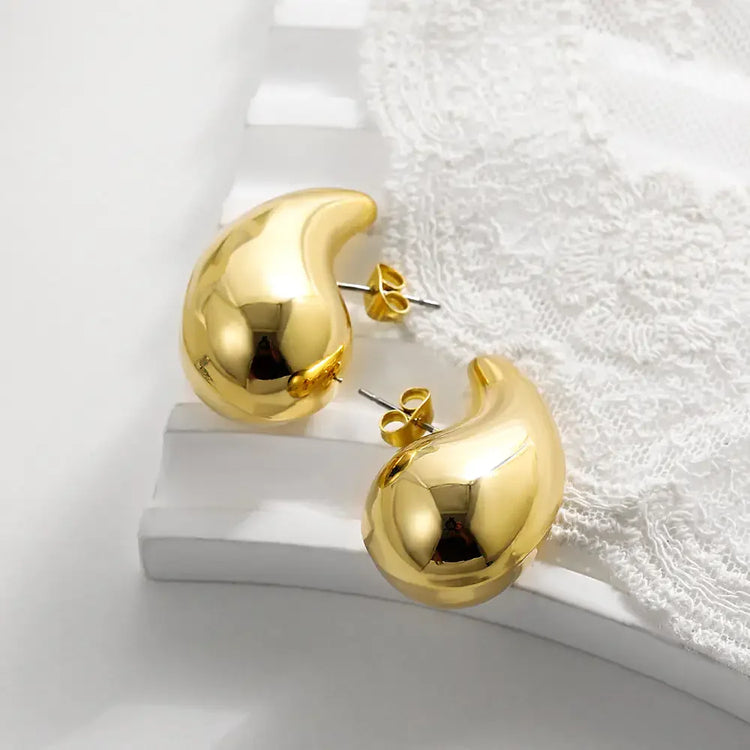 Unique gold abstract stud earrings on lace fabric, modern bold jewelry style