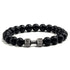 Matte black beaded bracelet with a unique silver dumbbell charm, perfect for bold style