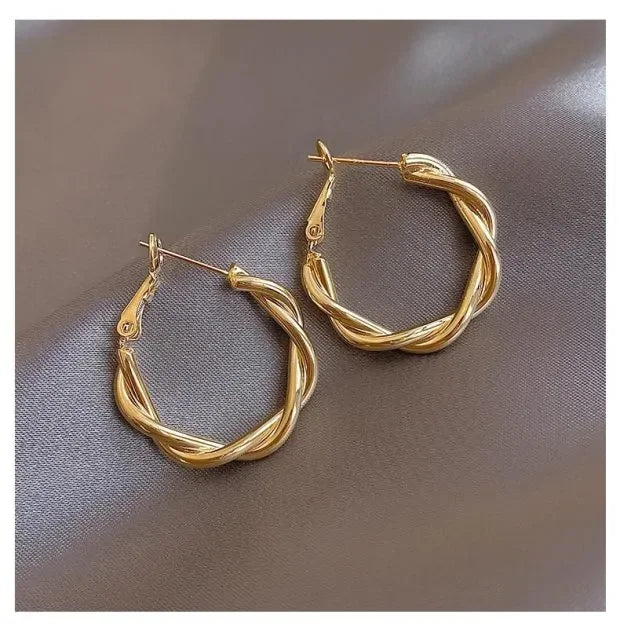 Intriguing twisted gold hoop earrings on satin, unique statement jewelry for stylish looks