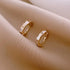 Elegant gold hoop earrings with unique geometric accents on soft beige fabric, inspiring curiosity.