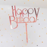 Rose gold Happy Birthday cake topper with playful font, surrounded by festive gold stars.