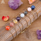 Colorful gemstone bead bracelets with gold chains, inviting curiosity, on rustic wood surface