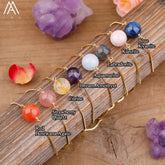Colorful gemstone bracelets with gold chains on wood, featuring unique crystal beads.