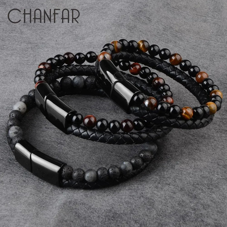Set of stylish beaded and braided leather bracelets with glossy black clasps on grey fabric