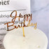 Elegant gold Happy Birthday cake topper on minimalist white frosted cake, perfect for unique celebrations