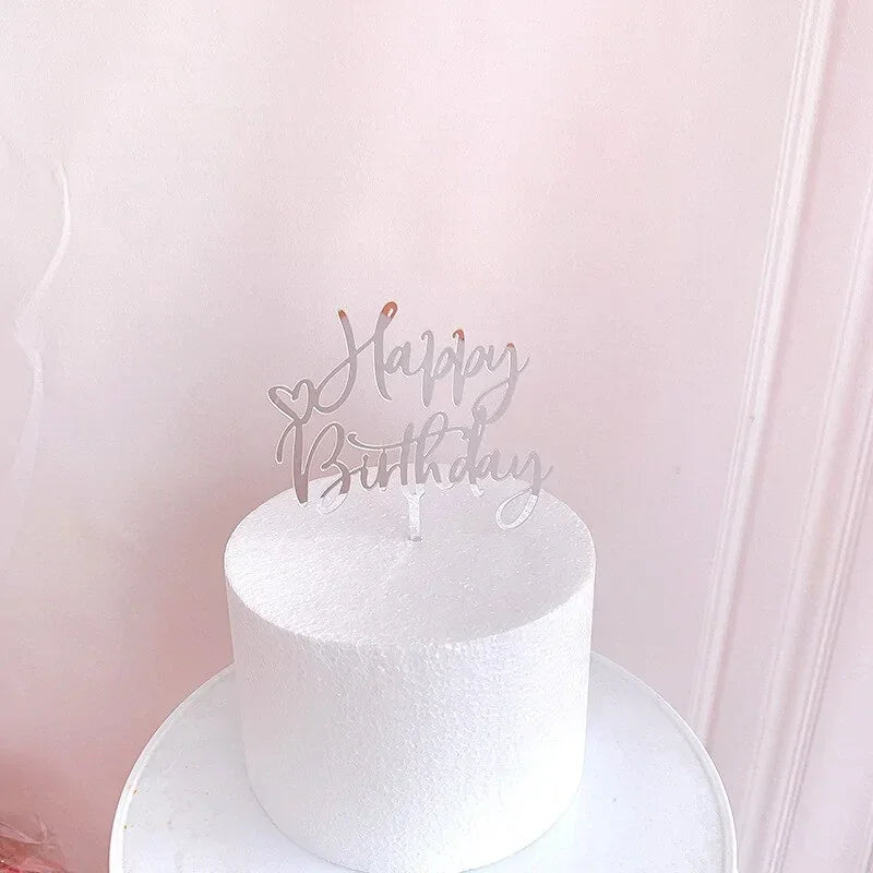 Elegant Happy Birthday acrylic cake topper with heart accent on simple white cake, unique celebration décor.