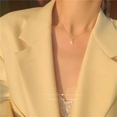Elegant gold necklace with teardrop pendant on a woman in a chic cream blazer, radiating unique style