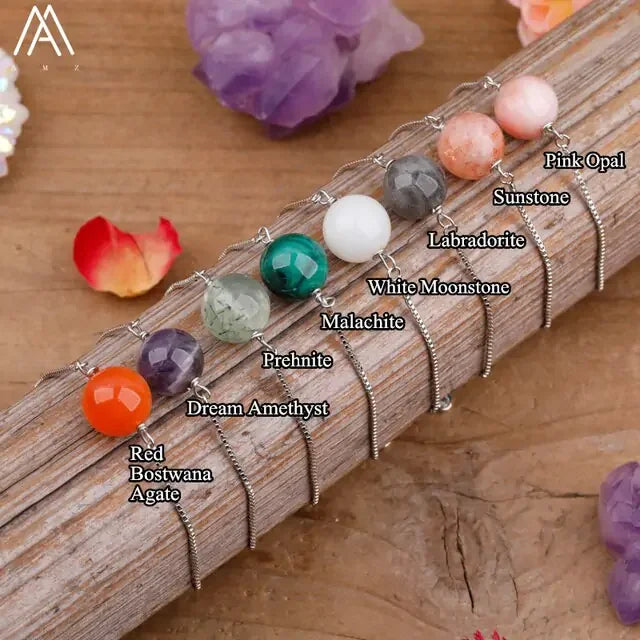 Discover unique gemstone pendants—Red Bostwana Agate, Dream Amethyst, Malachite and more—displayed on a rustic wood background, sparking curiosity for distinctive jewelry lovers.
