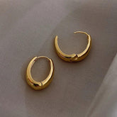 Elegant gold hoop earrings with a unique sculptural design on soft fabric, perfect for standout style