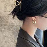 Elegant woman wearing bold gold hoop earrings and a unique gold hair clip, sparking curiosity