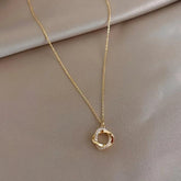 Elegant gold textured circle pendant necklace with sparkling stones on a soft beige background