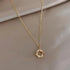 Elegant gold textured circle pendant necklace with sparkling stones on a soft beige background