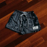 Intriguing black paisley print shorts with drawstring, unique patch design on wood floor