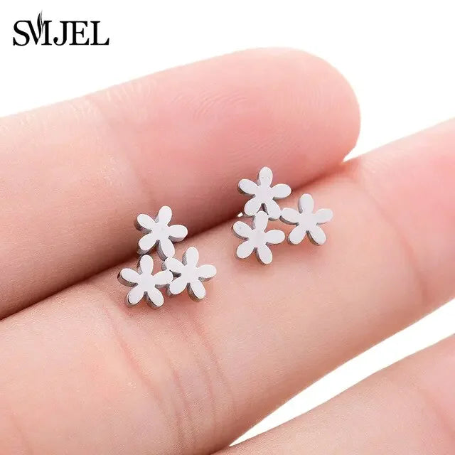 Delicate silver flower stud earrings on fingertips, unique and stylish minimalist jewelry