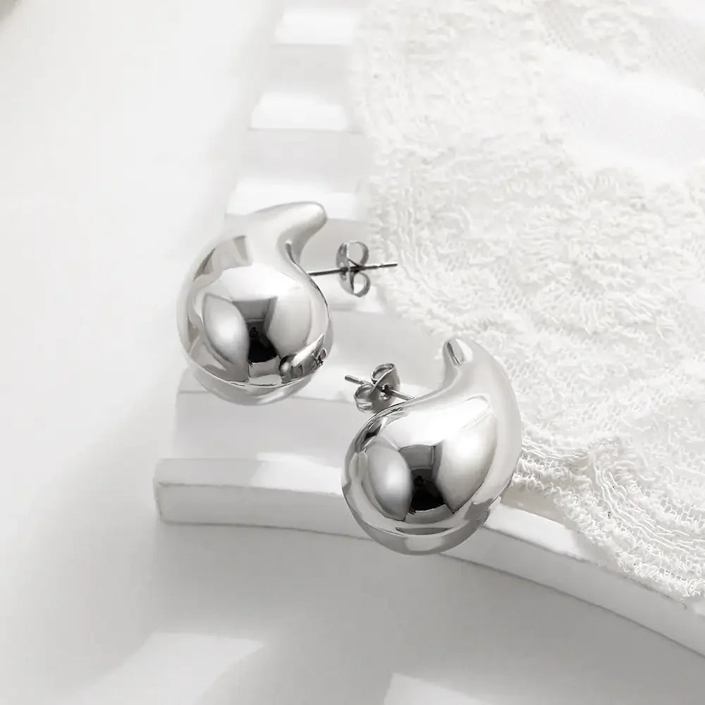 Shiny silver abstract stud earrings on elegant white lace, modern and unique jewelry design