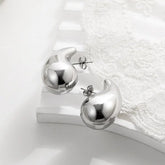 Shiny silver abstract stud earrings on elegant white lace, modern and unique jewelry design