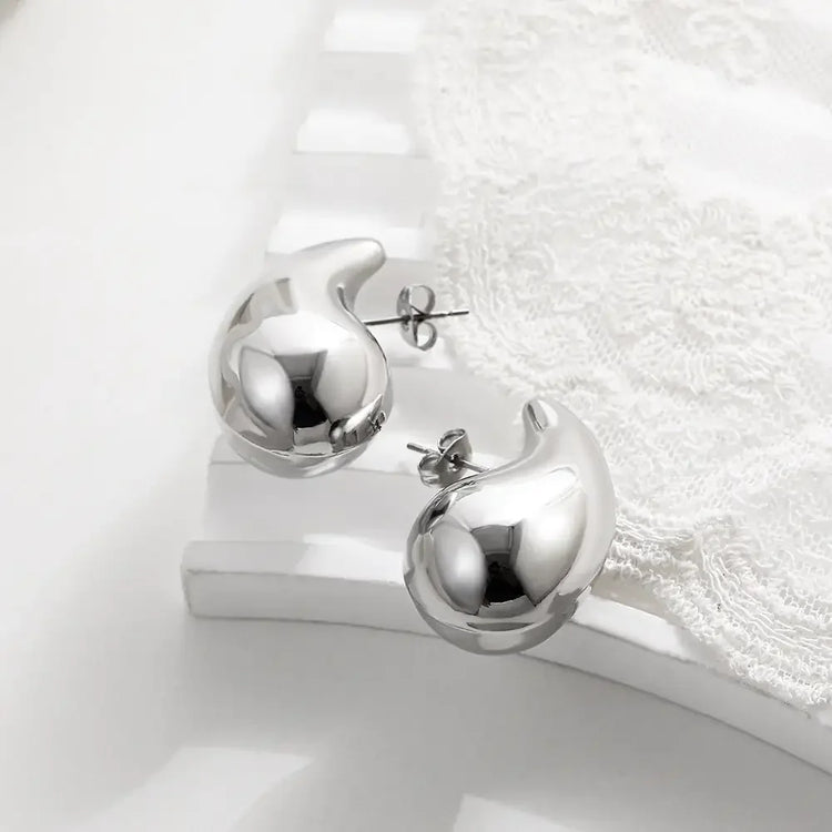 Shiny silver abstract stud earrings on elegant white lace, modern and unique jewelry design