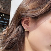 Elegant gold twisted circle stud earring, sparkling and unique, shown on a woman&