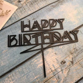 Modern geometric black Happy Birthday cake topper on rustic blue wood
