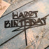 Modern geometric black Happy Birthday cake topper on rustic blue wood
