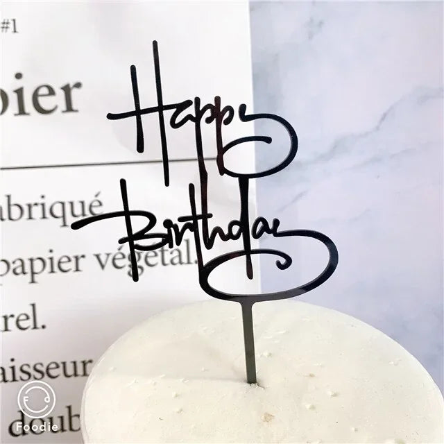 Chic black Happy Birthday cake topper elevates a minimalist white cake, sparking celebration curiosity.