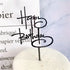 Chic black Happy Birthday cake topper elevates a minimalist white cake, sparking celebration curiosity.