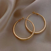 Elegant gold hoop earrings on soft satin fabric, inviting a touch of unique, chic style.