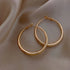 Elegant gold hoop earrings on soft satin fabric, inviting a touch of unique, chic style.