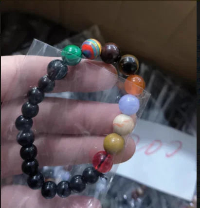 Hand holding a unique beaded bracelet with colorful stones, perfect for stylish, curious décor lovers.