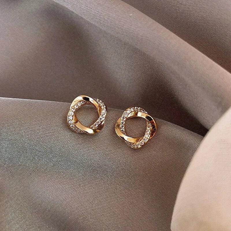 Dazzling gold knot stud earrings with sparkling crystals on elegant mauve fabric, unique jewelry