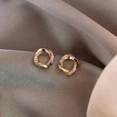 Dazzling gold knot stud earrings with sparkling crystals on elegant mauve fabric, unique jewelry