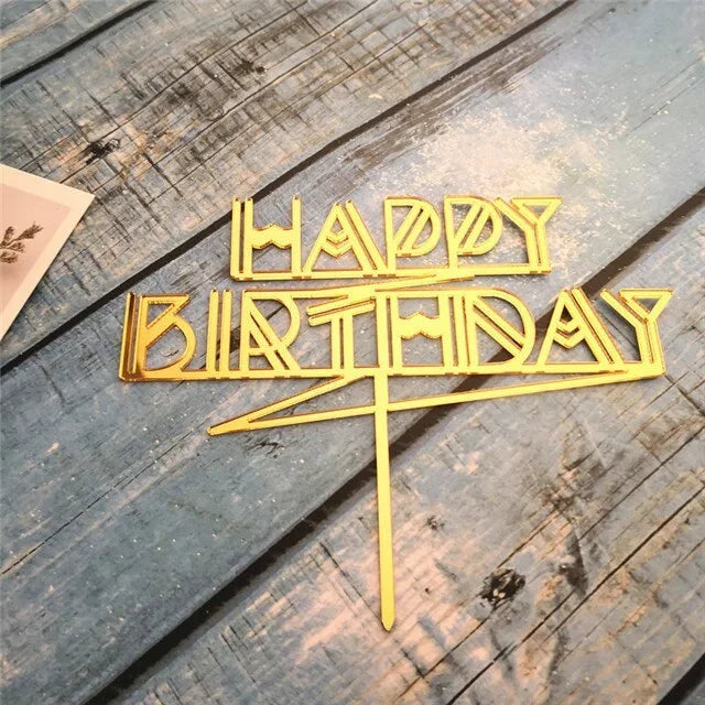 Elegant gold Happy Birthday cake topper on rustic blue wooden surface, perfect for unique celebrations