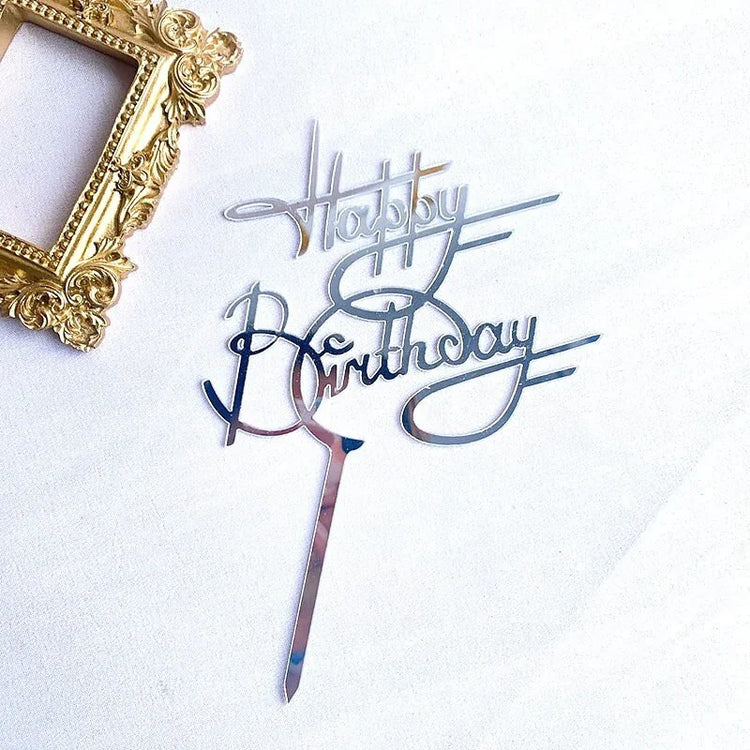 Shiny silver Happy Birthday cake topper with elegant script, beside ornate gold frame