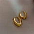 Sleek gold hoop earrings on soft beige fabric, radiating modern minimalist luxury.