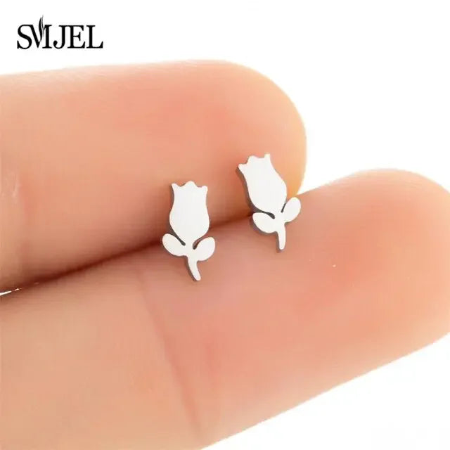 Delicate silver rose stud earrings held on fingertips, perfect for unique, stylish looks.