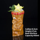 Whimsical tiki face ceramic mug with carved details, filled with ice, mint, and starfruit slice