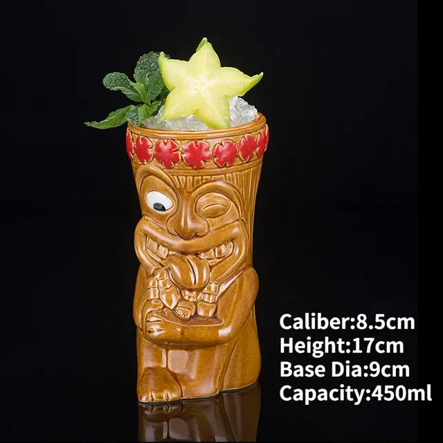 Whimsical tiki face ceramic mug with carved details, filled with ice, mint, and starfruit slice