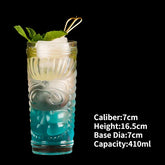 Intriguing tiki cocktail glass with blue drink, ice, mint garnish and unique sculpted design.